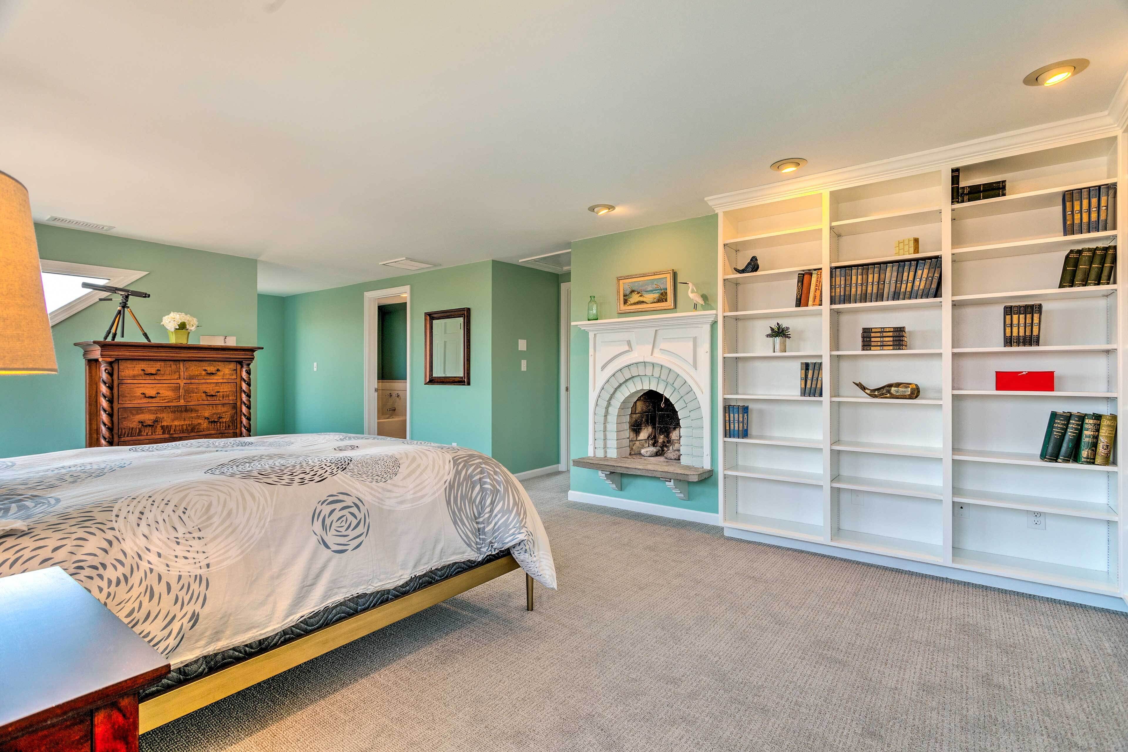 A bedroom with a bed, a fireplace, and a bookshelf.