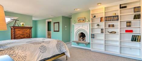 A bedroom with a bed, a fireplace, and a bookshelf.