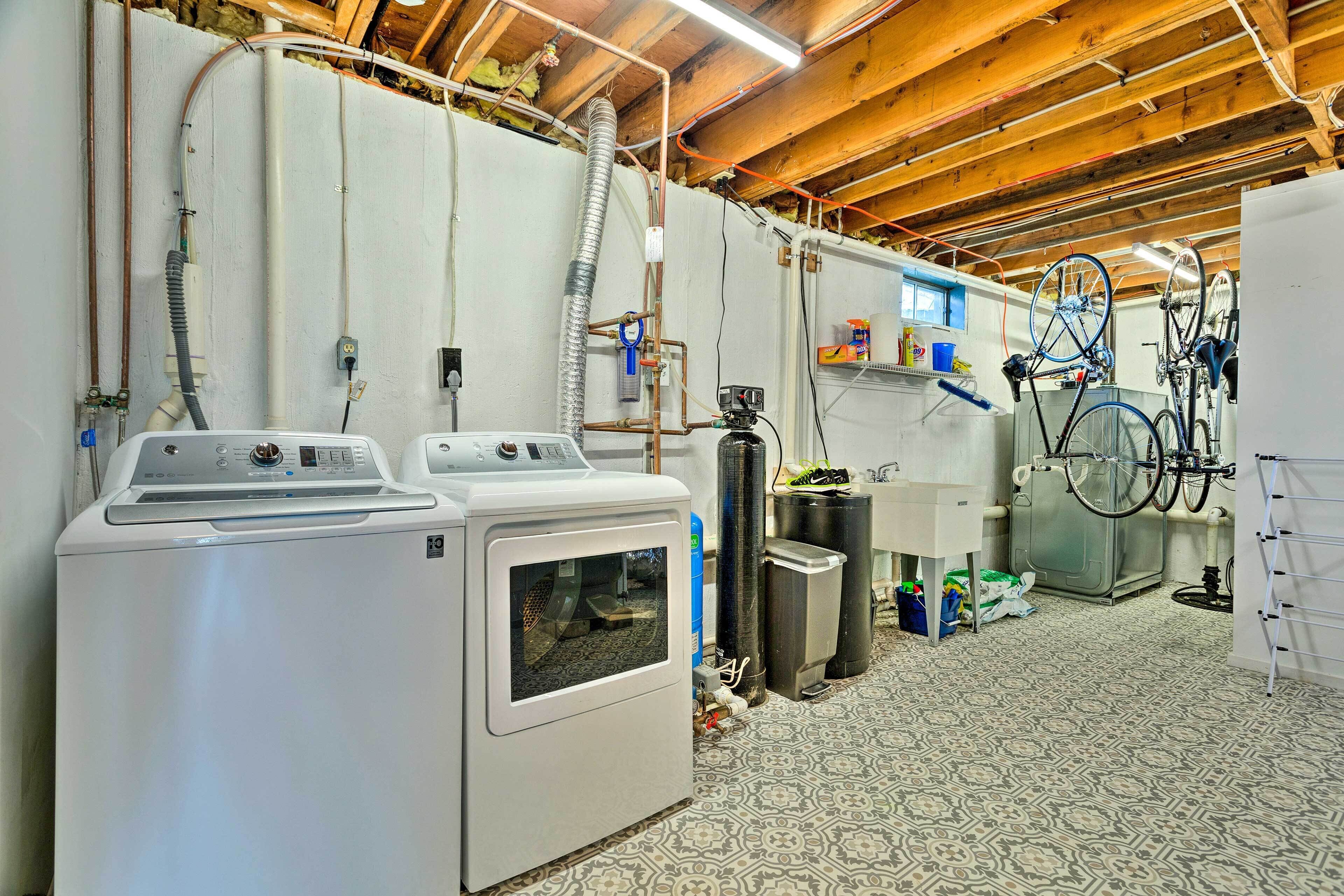 A laundry room with two front-loading washers, a water heater, and various hoses and pipes.