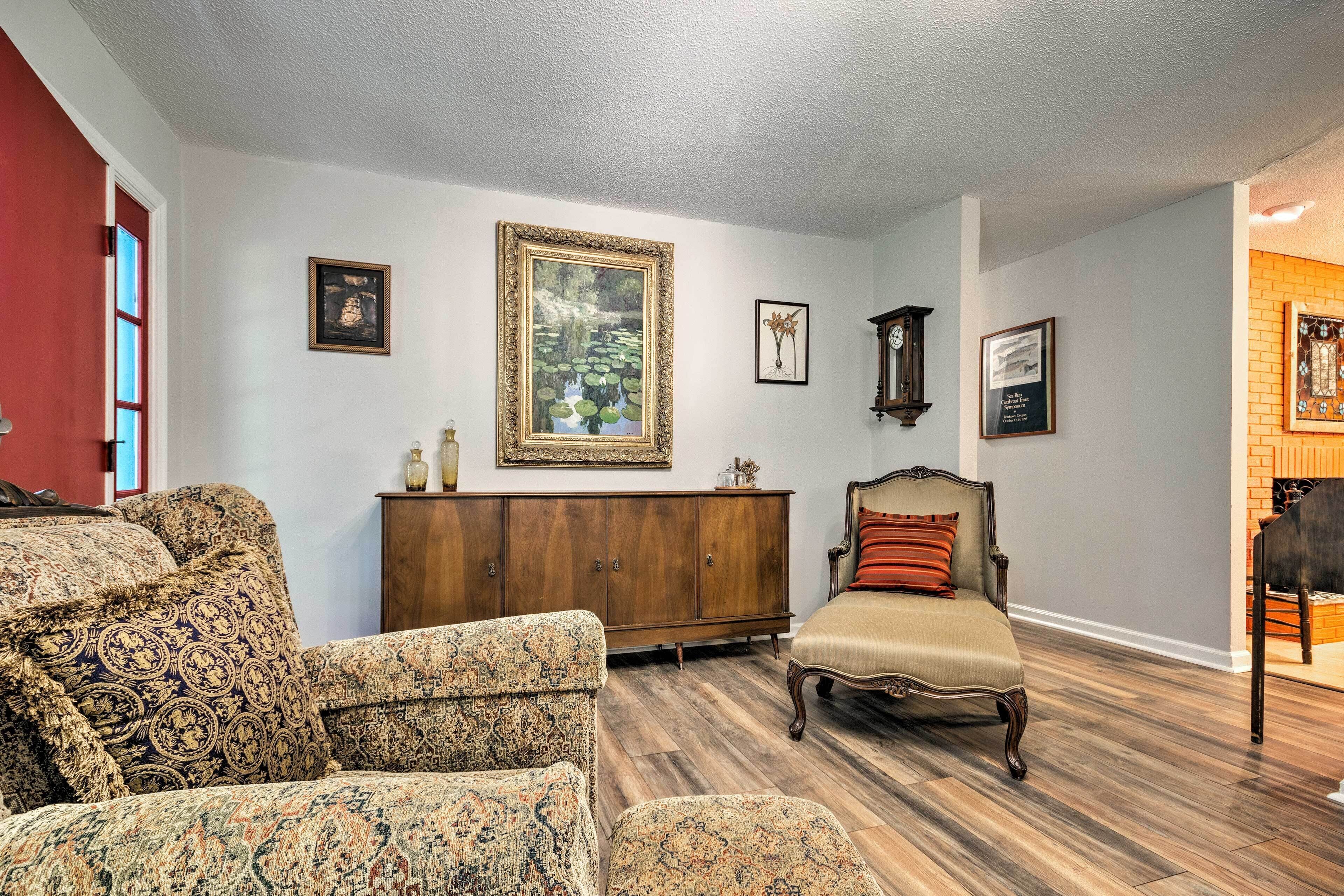 A living room with patterned furniture, a wooden cabinet, and framed artwork on the walls.