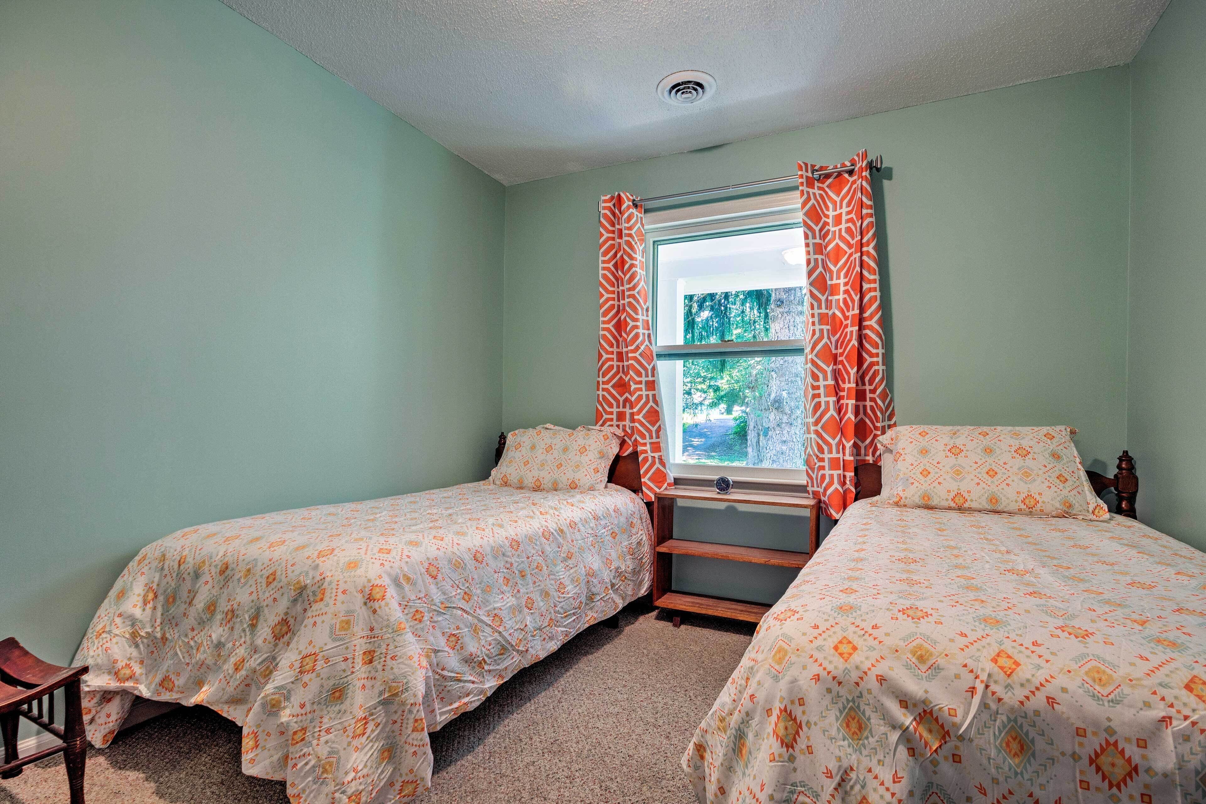 Une chambre avec deux lits, une fenêtre avec des rideaux et un sol recouvert d’une moquette.