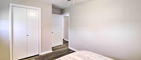Un dormitorio con cama, ventilador de techo y un pasillo que conduce a otra habitación.