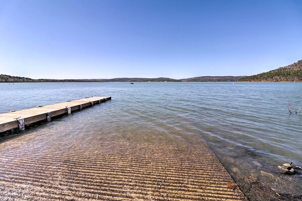 A wooden dock extending into calm water with a clear sky above.