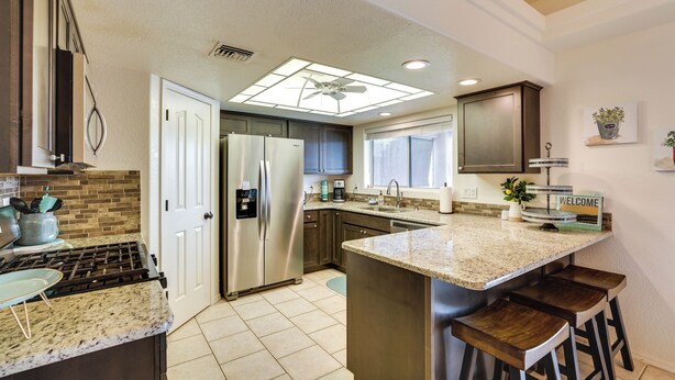A modern kitchen with a central island, stainless steel appliances, and a large window providing natural light. - 4 Mi to Lake Access: Home w/ Lake & Mtn Views! (Lake Havasu City)