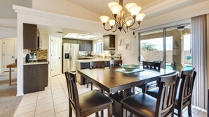 A spacious kitchen with a central island, a dining area with a chandelier, and a view of a pool through large sliding glass doors. - 4 Mi to Lake Access: Home w/ Lake & Mtn Views! (Lake Havasu City)