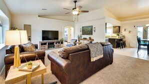 A spacious living room with a brown leather sofa, a television, and a ceiling fan. - 4 Mi to Lake Access: Home w/ Lake & Mtn Views! (Lake Havasu City)