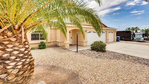 A single-story building with a beige exterior, a gravel driveway, and a palm tree in the foreground. - 4 Mi to Lake Access: Home w/ Lake & Mtn Views! (Lake Havasu City)