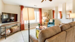 Un salon avec un canapé, un téléviseur et un ventilateur de plafond.