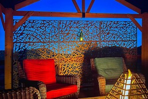 A covered outdoor seating area with wicker furniture and a decorative metal screen. - Deck & Indoor Pickleball Court: West Sedona Home! (Sedona)