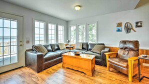 Ein Wohnzimmer mit einem Ecksofa, einem Ledersessel, einem Holztisch und einem kleinen Beistelltisch.