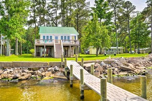 A lakeside cabin with a dock, surrounded by trees and a grassy area. - Coastal Escape: Bayfront Home w/ Dock & Views (Aurora)