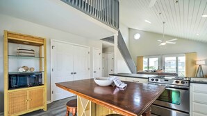 Una cocina moderna con una mesa de madera, electrodomésticos de acero inoxidable y un horno empotrado.