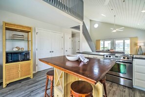 Een moderne keuken met een houten tafel, roestvrijstalen apparatuur en een inbouwoven.