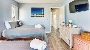 Un dormitorio con cama, ventilador de techo, televisor y cómoda.