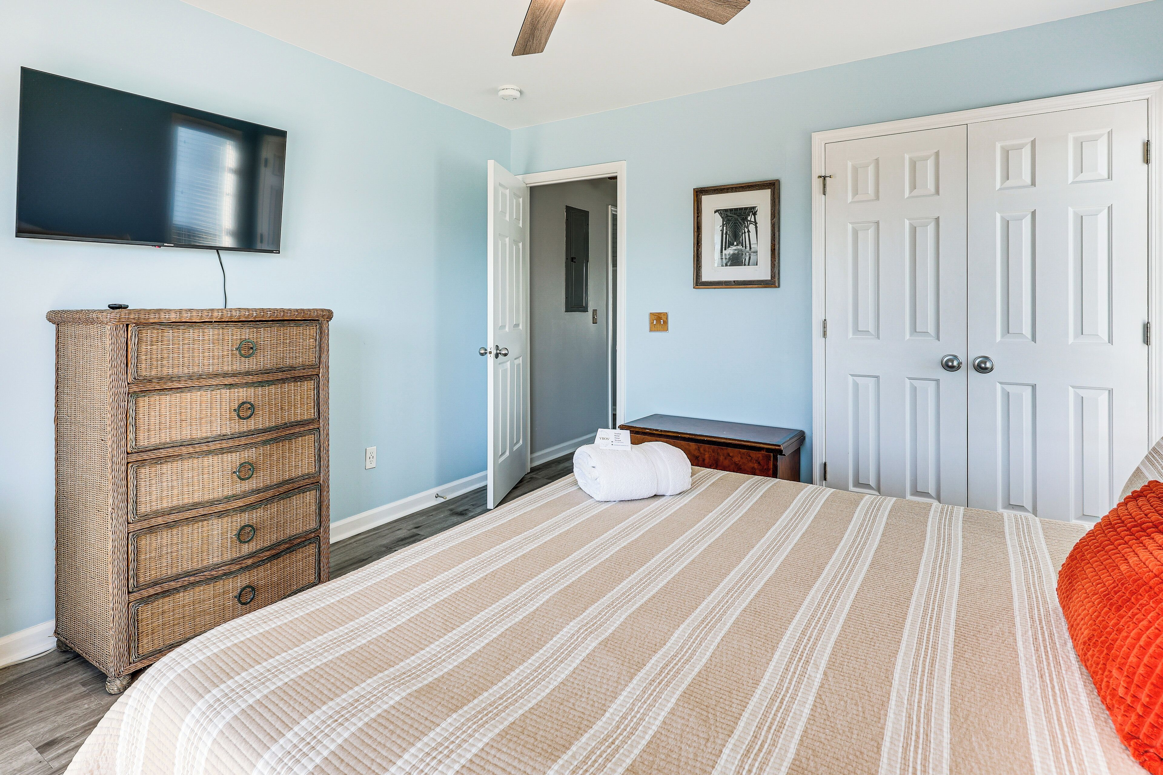 A bedroom with a bed, a dresser, a television, and a door.