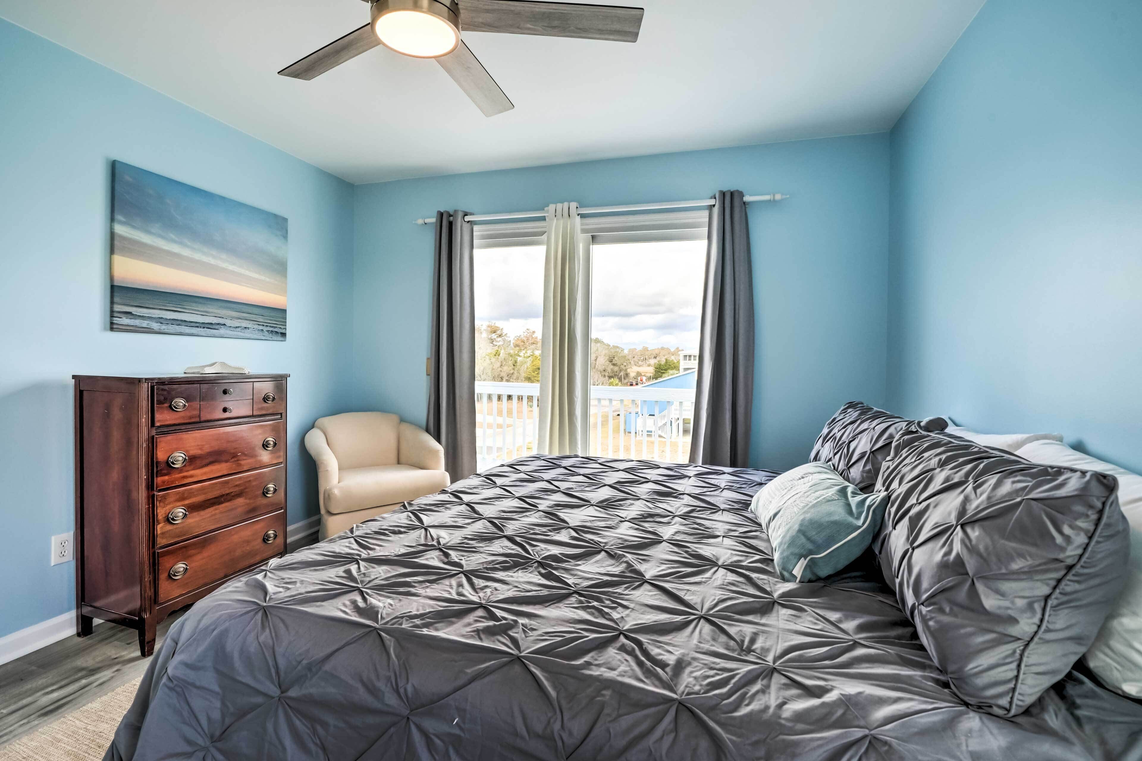 Une chambre à coucher comprenant un lit, une commode, une chaise et un ventilateur de plafond.