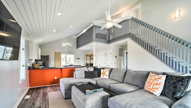 A spacious living area with a grey sectional sofa, a coffee table, and a staircase with a railing. - For Families & Pets! Oceanside Oak Island Getaway (Oak Island)