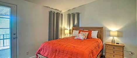 Ein Schlafzimmer mit einem hölzernen Bett, einem Nachttisch mit Lampe und einem Fenster mit Jalousien.