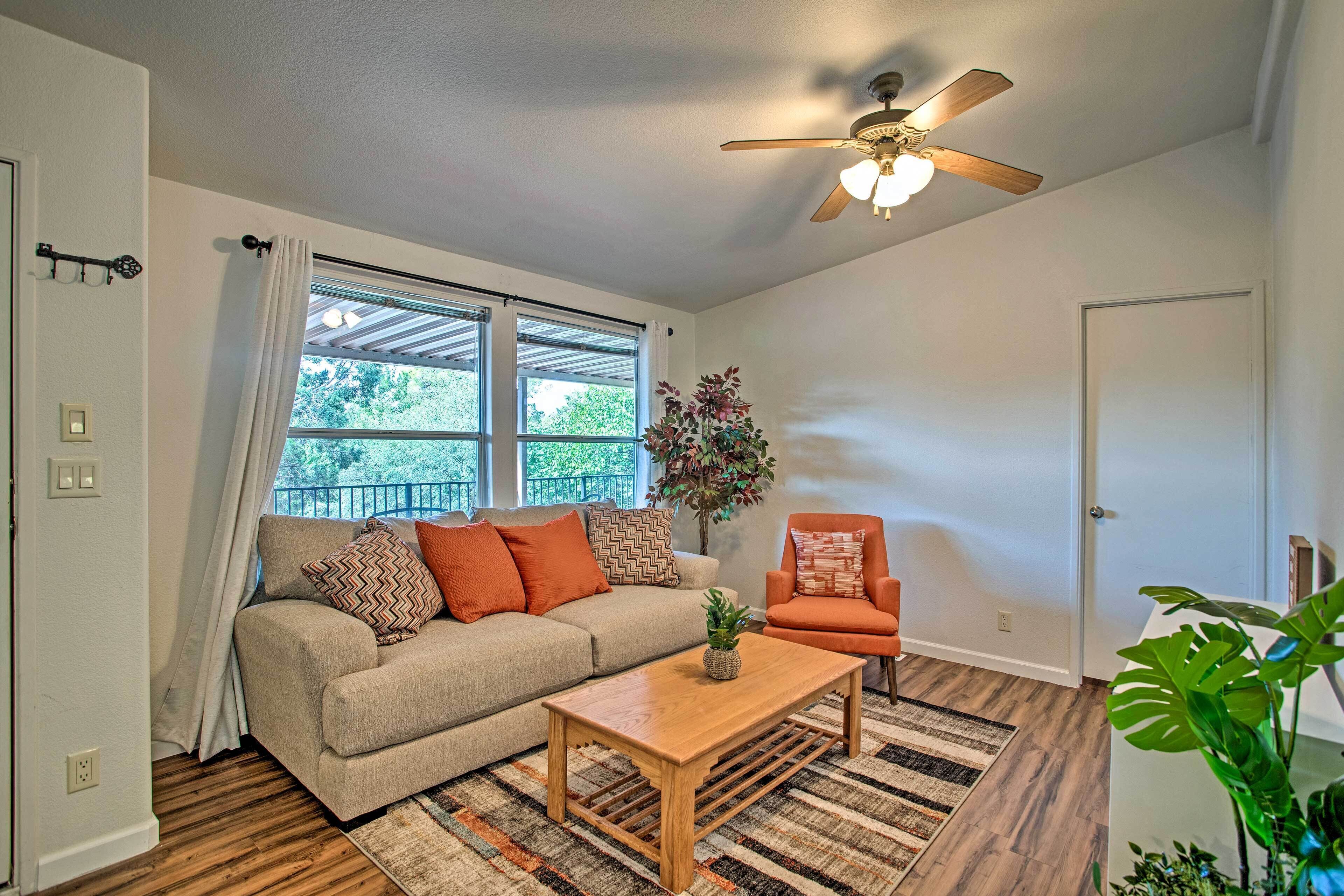 A living room with a sofa, armchair, coffee table, and a ceiling fan.