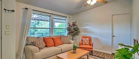 A living room with a sofa, armchair, coffee table, and a ceiling fan.