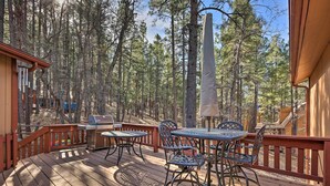 Eine Holzterrasse mit Tisch und Stühlen, umgeben von hohen Kiefern.