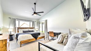 A modern bedroom with a bed, desk, and chair, a ceiling fan, and large windows. - Pool, BBQ & Patio: Gilbert Getaway Near Golfing (Gilbert)