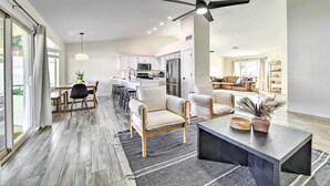 A modern kitchen with white cabinets, a black ceiling fan, and a dining area with a table and chairs. - Pool, BBQ & Patio: Gilbert Getaway Near Golfing (Gilbert)