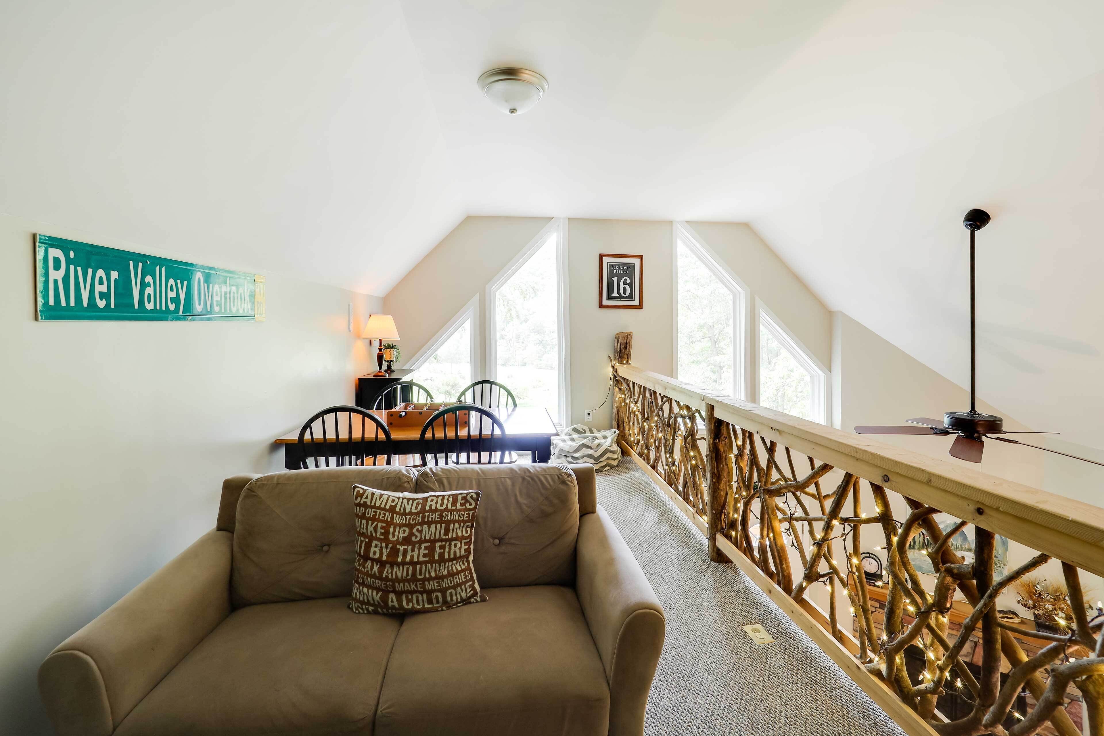 Ein gemütliches Zimmer mit einer Couch, einem Esstisch mit Stühlen, einem Holzbalken und einem Schild mit der Aufschrift 'River Valley Overlook'.