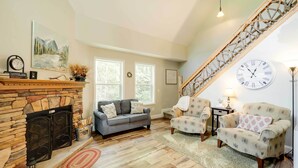 A cozy living room with a fireplace, a staircase, and a large wall clock. - 'greystone' Creekside Cabin: Hike, Fish & Explore! (Elk Park)