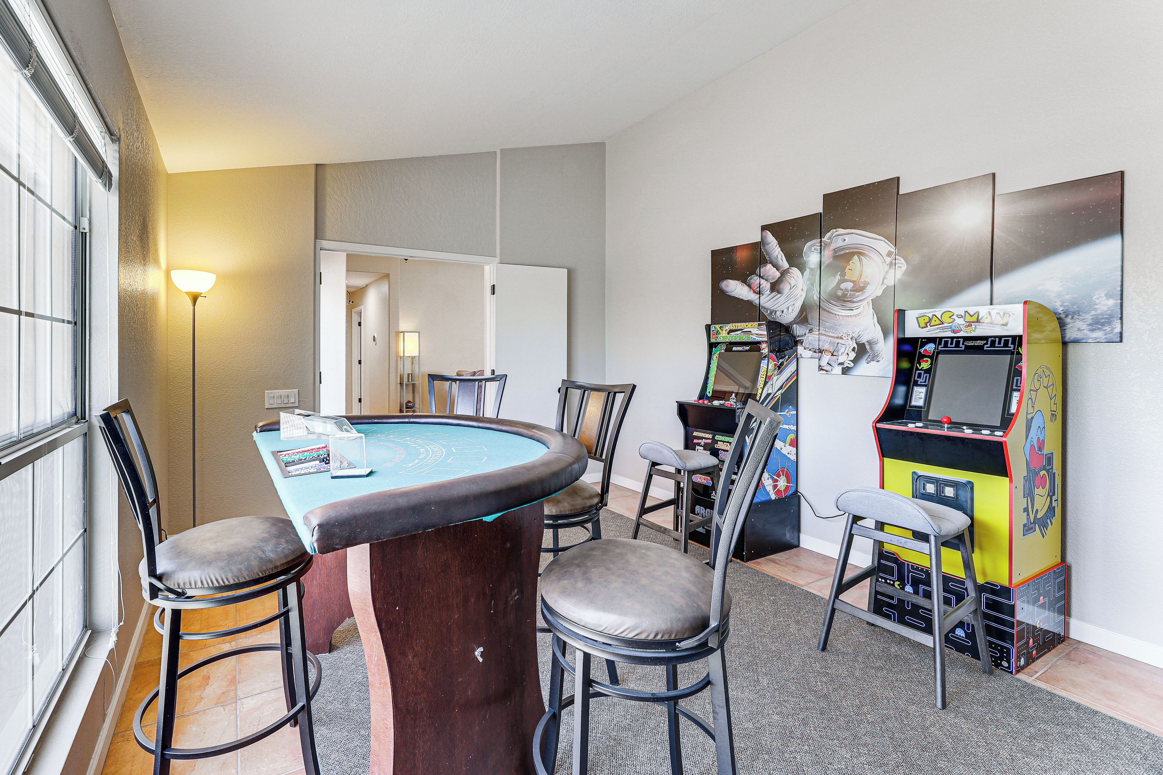 A room with a pool table, bar stools, arcade games, and a wall with space-themed artwork.