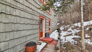 Une maison en bois avec une porte rouge et un petit porche.