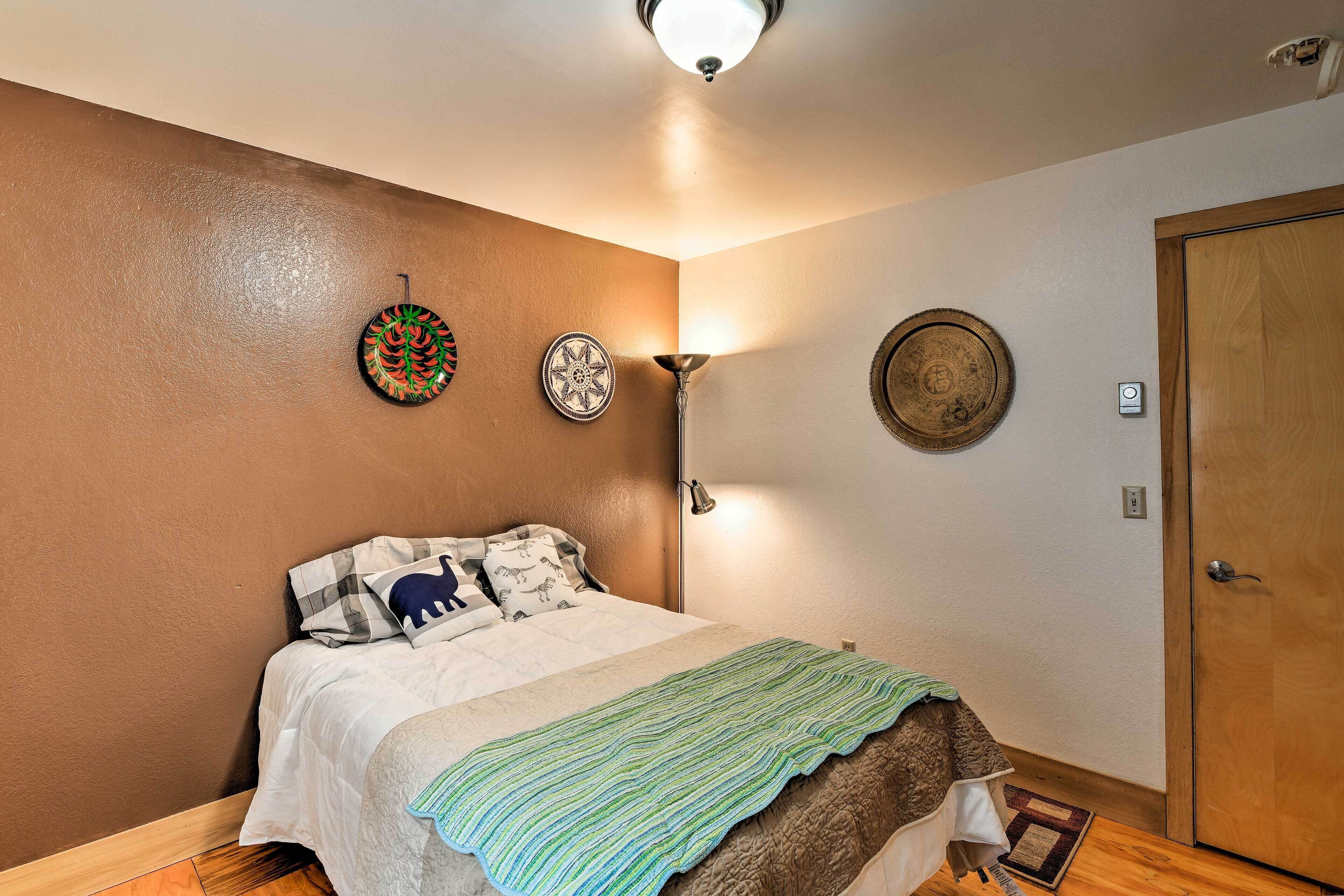 A bedroom with a bed, a wall-mounted lamp, and decorative plates.