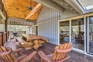 A wooden deck with a large table and chairs, a ceiling fan, and a view of the surrounding trees. - 40-acre Mtn-view Retreat w/ Hot Tub in Banner Elk! (Banner Elk)