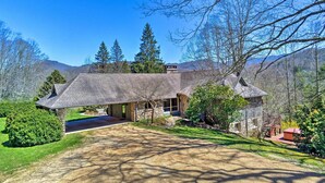 A large, two-story stone house with a covered driveway and a well-maintained lawn.