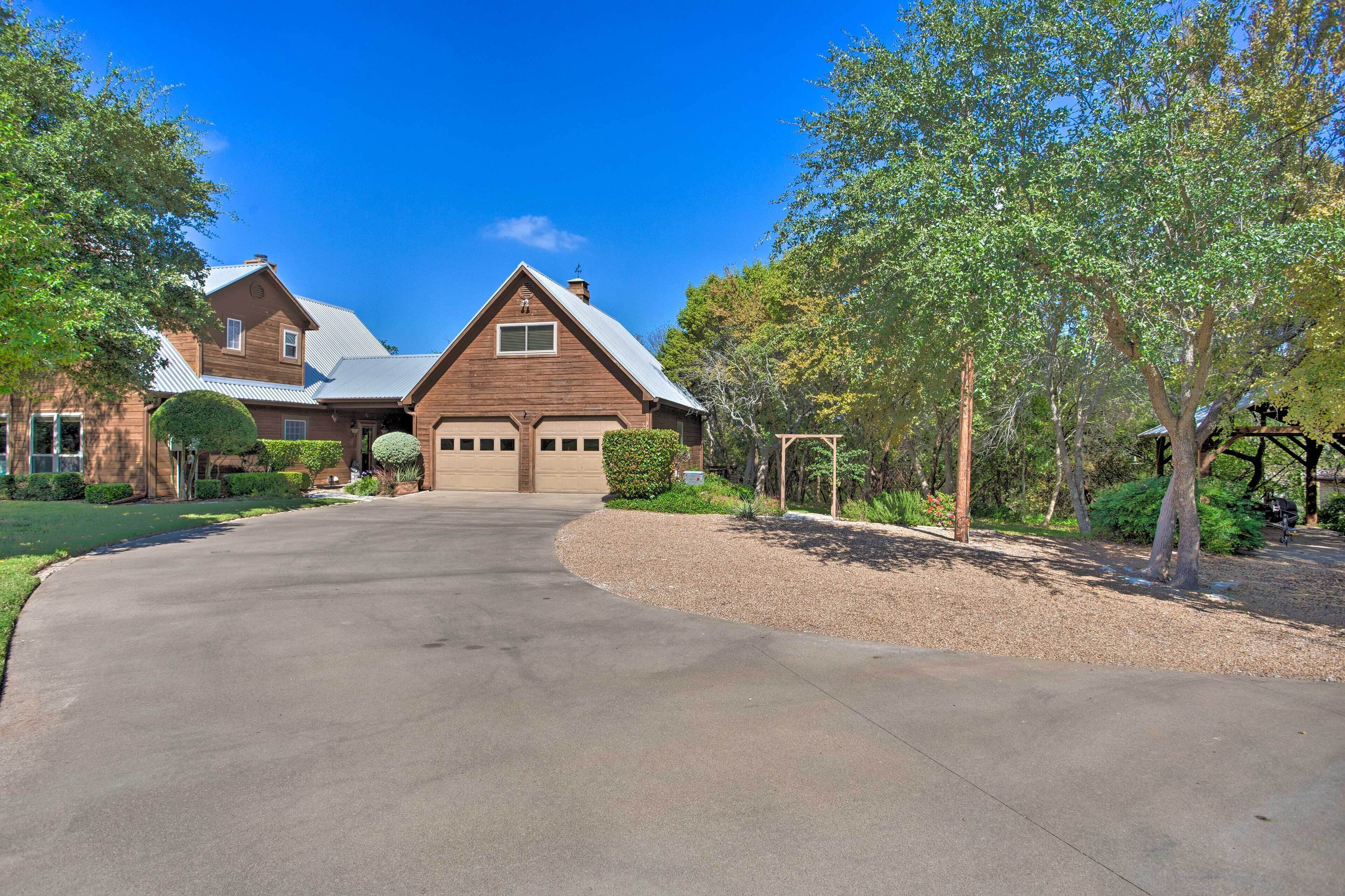 A two-story house with a garage, surrounded by trees and a well-maintained lawn.