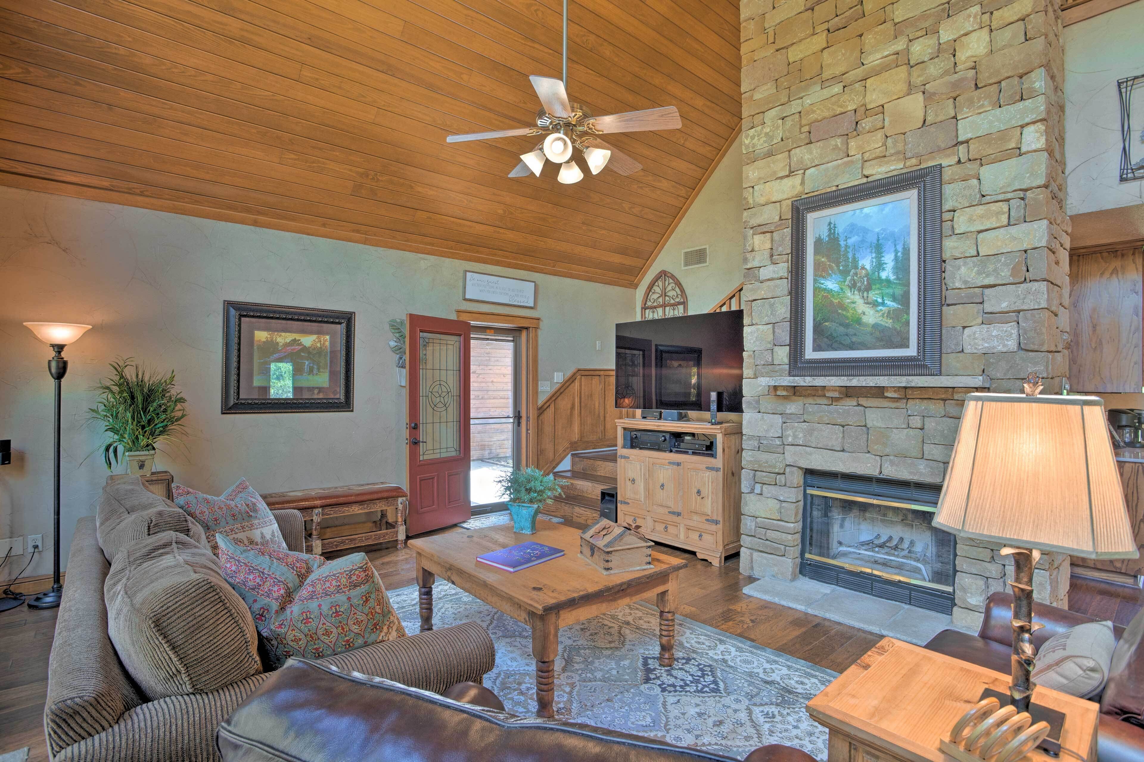 A cozy living room with a stone fireplace, wooden ceiling, and a comfortable seating area.