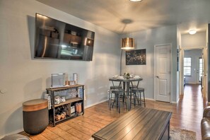 A modern living room with a flat-screen TV, a round dining table with chairs, a wooden bench, and a kitchen area with a cart and storage. - Branson Condo w/ Balcony on Ledgestone Golf Course (Branson West)