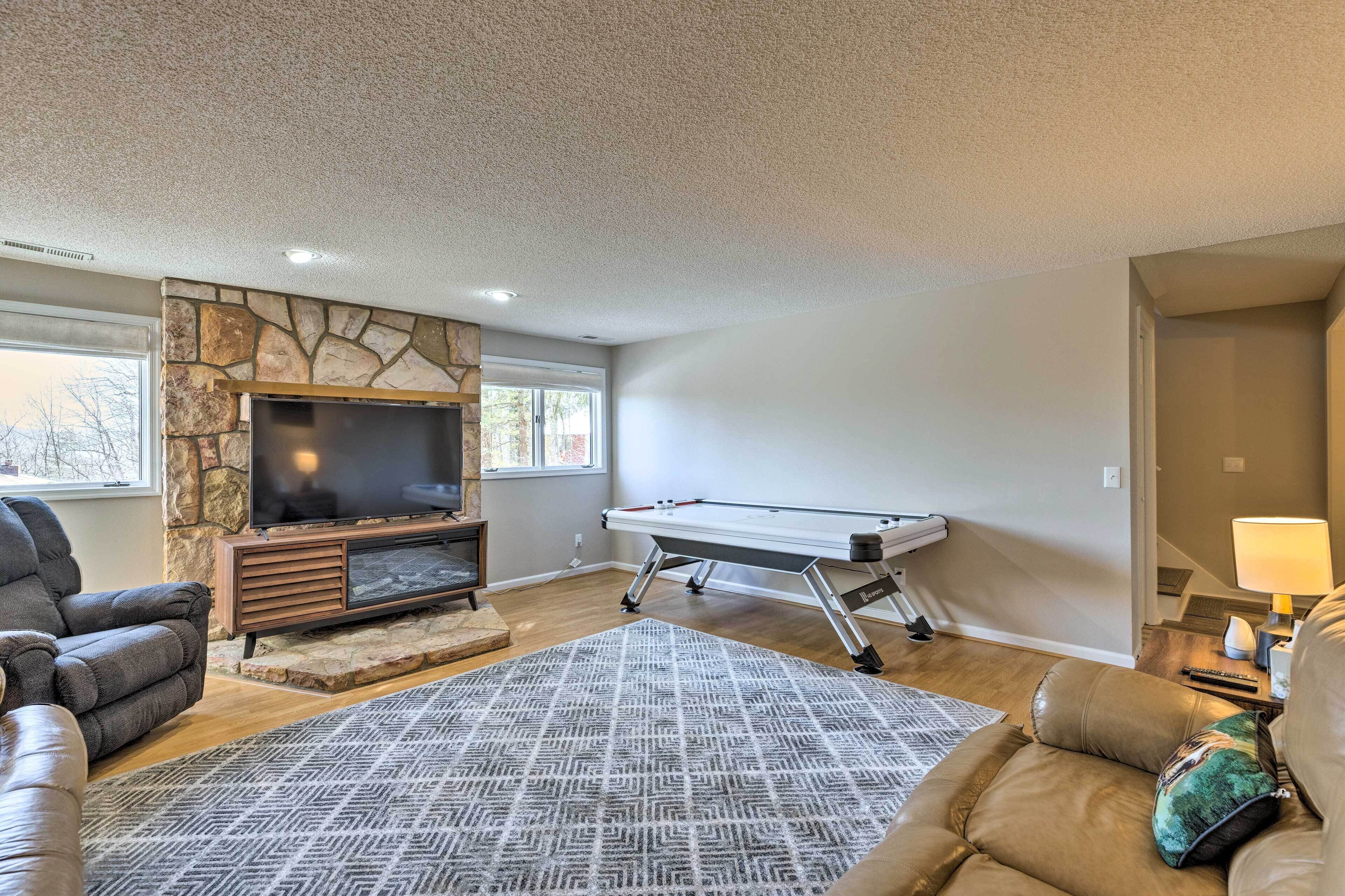 A living room with a stone fireplace, a flat-screen TV, a pool table, and leather sofas.