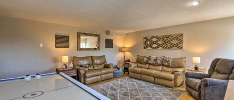 A living room with a pool table, two leather sofas, a patterned rug, and a wall-mounted mirror.