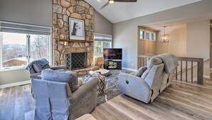 A spacious living room with a stone fireplace, comfortable seating, and a large TV. - Massanutten Resort Home w/ Deck + Mountain Views! (McGaheysville)