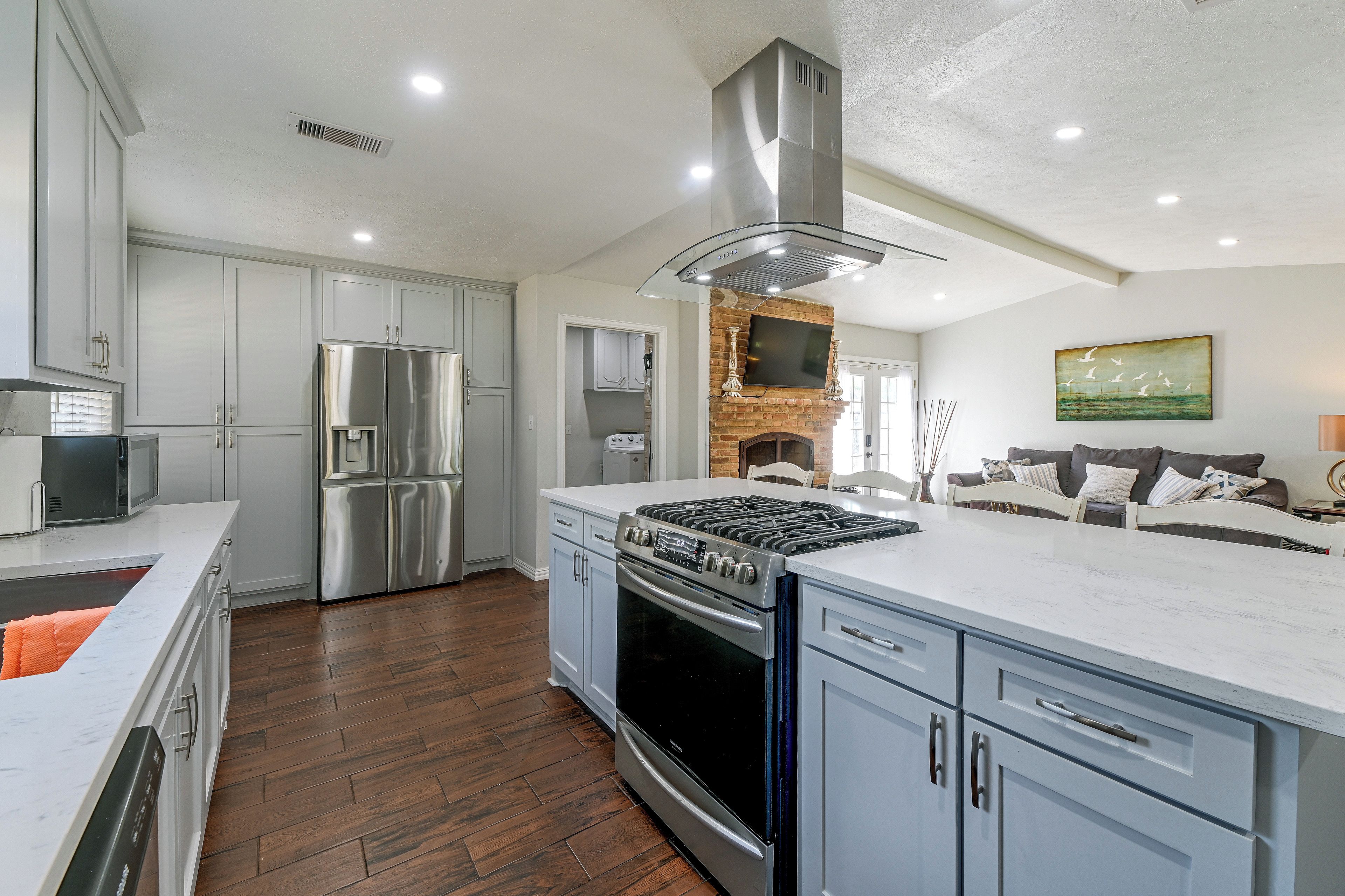 A modern kitchen with stainless steel appliances, a brick fireplace, and a large island.
