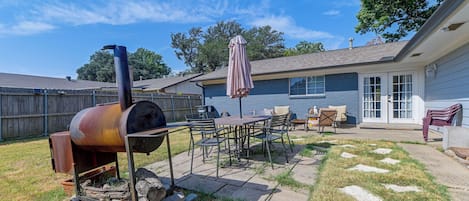 A backyard with a barbecue grill, outdoor furniture, and a patio area.