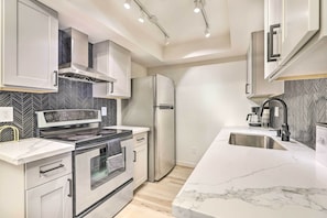 A modern kitchen with a stainless steel stove, oven, and refrigerator, white cabinetry, and a marble countertop. - 1 Mi to Dtwn Chandler: Townhome w/ Community Pool (Chandler)