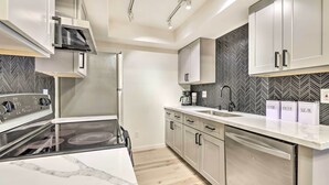 Une cuisine moderne dotée d’une cuisinière intégrée, de meubles en acier inoxydable, d’un lave-vaisselle et d’un dosseret décoré d’un motif en chevrons.