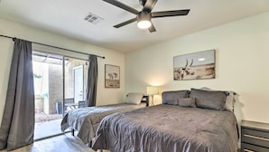 Une chambre avec deux lits, un ventilateur de plafond, une lampe et des œuvres d’art accrochées aux murs.