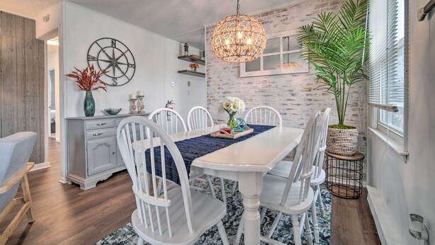 A dining area with a white table and chairs, a decorative globe wall art, and a hanging light fixture.