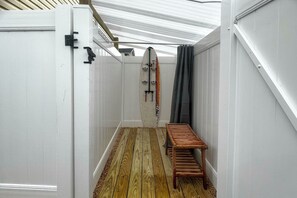 A narrow hallway with a wooden floor, a bench, and a surfboard leaning against the wall. - Coastal Brigantine Retreat - Walk to Beach! (Brigantine)