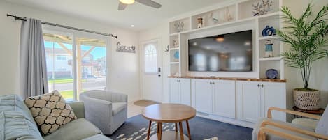 Una sala de estar moderna con un sofá, sillones, un televisor y un ventilador de techo.