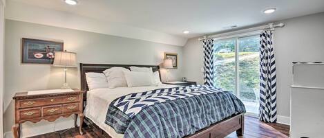 A bedroom with a large bed, wooden nightstands, and a window with curtains.