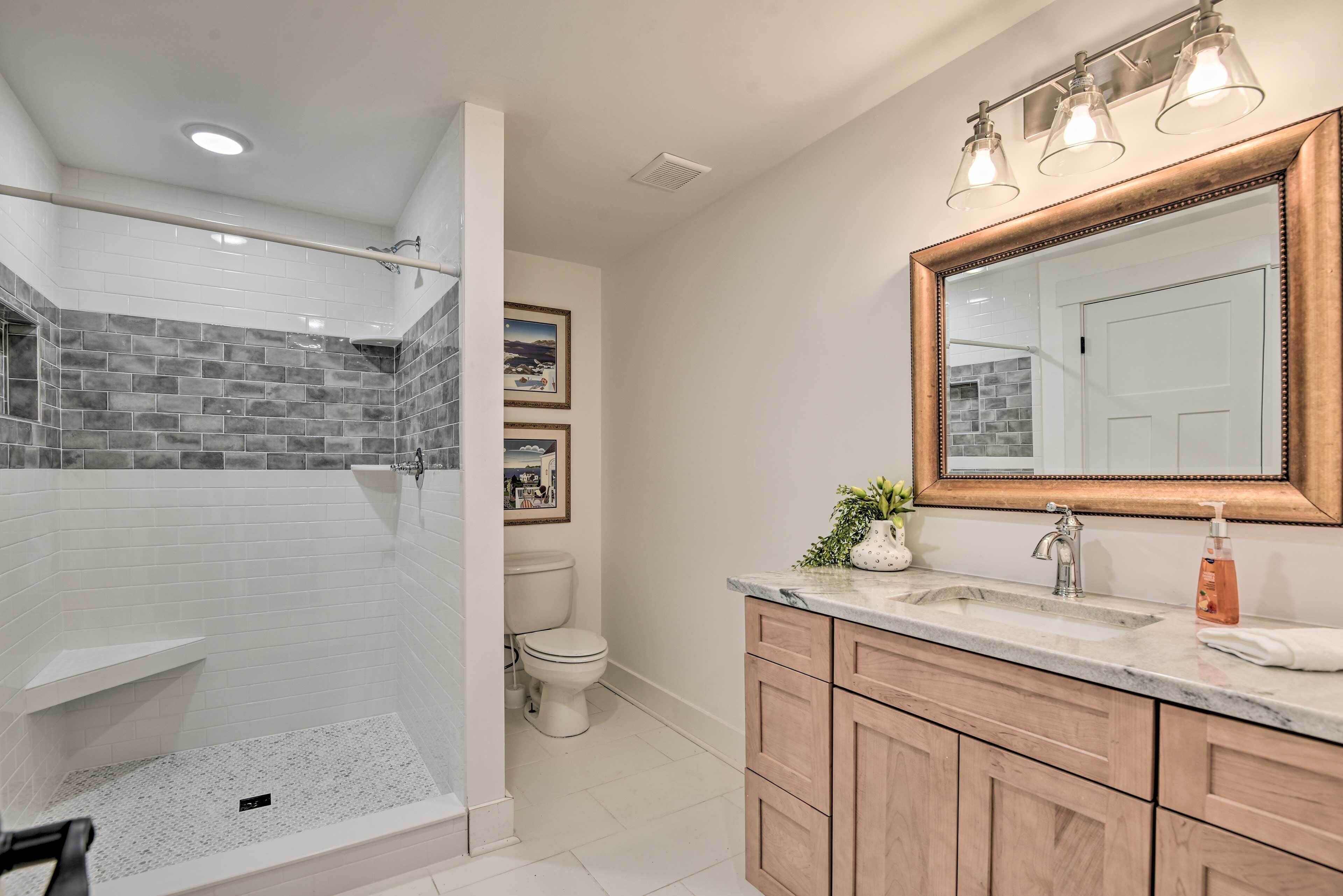 A modern bathroom with a shower, toilet, and vanity with a large mirror.